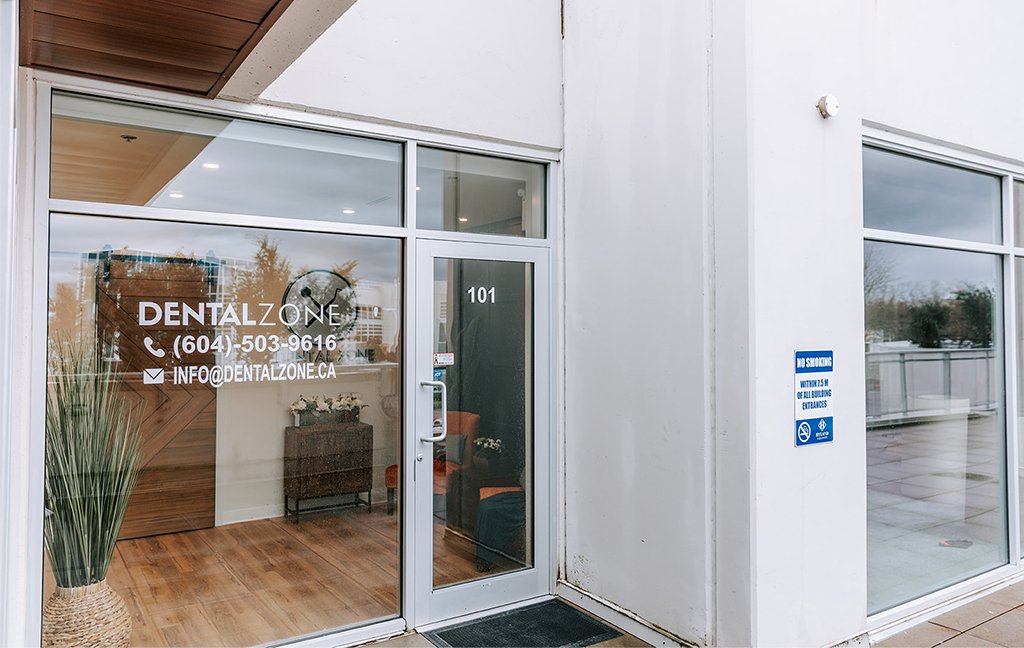 Glass front door of Dental Zone, suite 101, with the logo and phone number on the window.